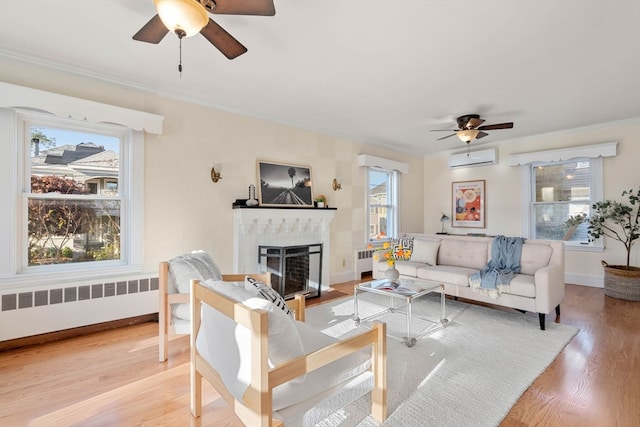 living room with light wood-type flooring, a wealth of natural light, ceiling fan, and radiator