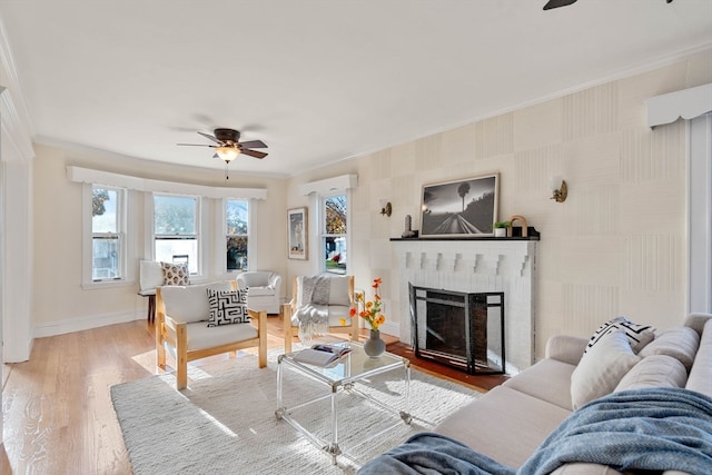 living room with a brick fireplace, hardwood / wood-style flooring, crown molding, and ceiling fan