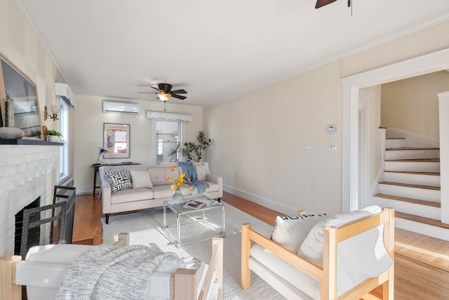 living room featuring ceiling fan, ornamental molding, light wood-type flooring, and a wall mounted air conditioner