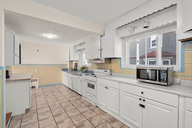 kitchen with white cabinetry, white appliances, a healthy amount of sunlight, and light tile patterned flooring