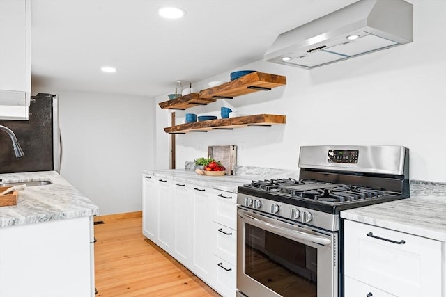 kitchen featuring white cabinets, light stone countertops, light wood-type flooring, range hood, and stainless steel appliances