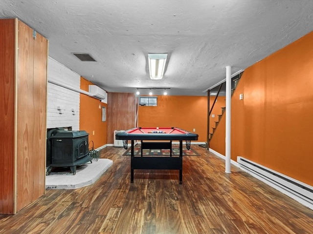 182 W Main St, Westborough, MA 01581 - recreation room with a baseboard heating unit, wood finished floors, a wood stove, a wall mounted air conditioner, and baseboards