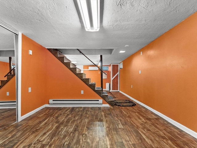 182 W Main St, Westborough, MA 01581 - finished below grade area with stairs, wood finished floors, baseboards, a baseboard heating unit, and a textured ceiling