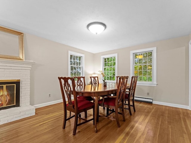 182 W Main St, Westborough, MA 01581 - dining area featuring a baseboard heating unit, wood finished floors, baseboards, and a brick fireplace