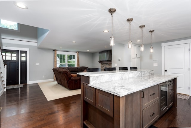 kitchen with a kitchen island, light stone counters, dark wood-type flooring, and wine cooler