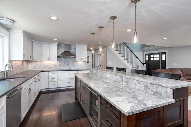 kitchen with sink, dark hardwood / wood-style flooring, wall chimney exhaust hood, decorative backsplash, and dishwasher