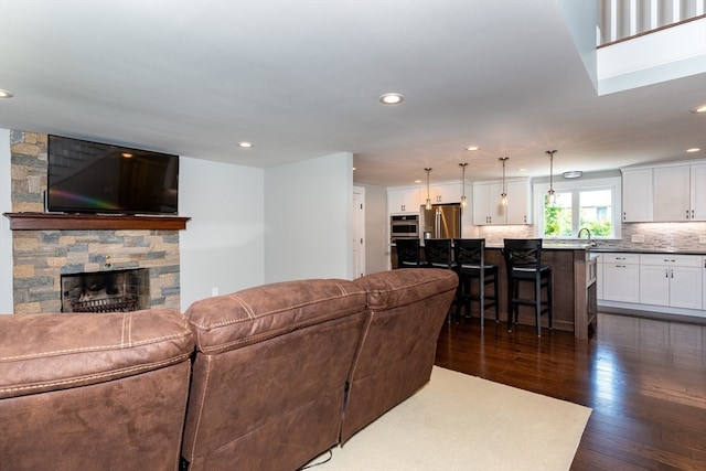 living room featuring dark wood-type flooring and a stone fireplace