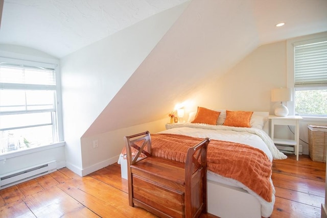 bedroom with light wood finished floors, lofted ceiling, and a baseboard radiator