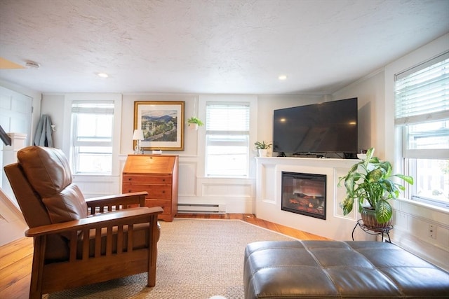 living room featuring a decorative wall, plenty of natural light, wood finished floors, and a baseboard radiator