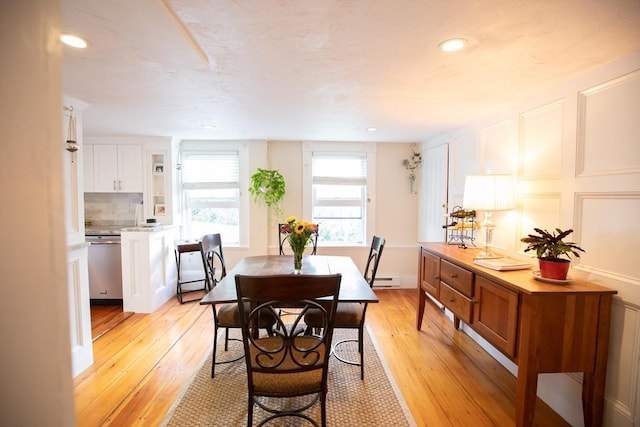dining area with recessed lighting, baseboard heating, a decorative wall, and light wood-type flooring