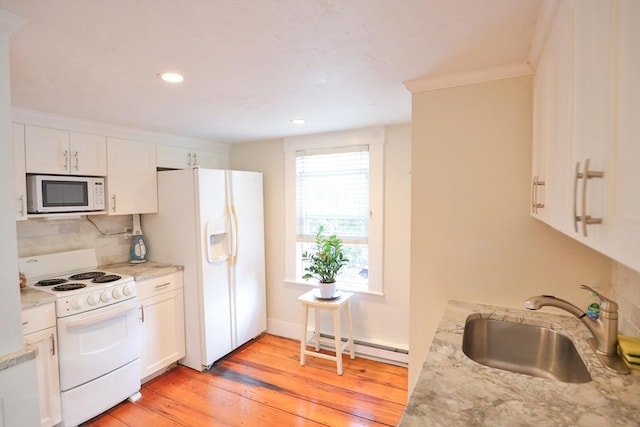 kitchen with a sink, a baseboard radiator, white appliances, and white cabinets