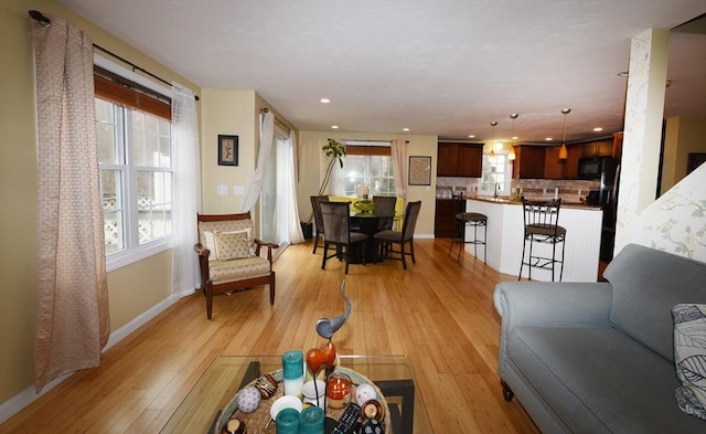 living room with a wealth of natural light, light wood-type flooring, baseboards, and recessed lighting