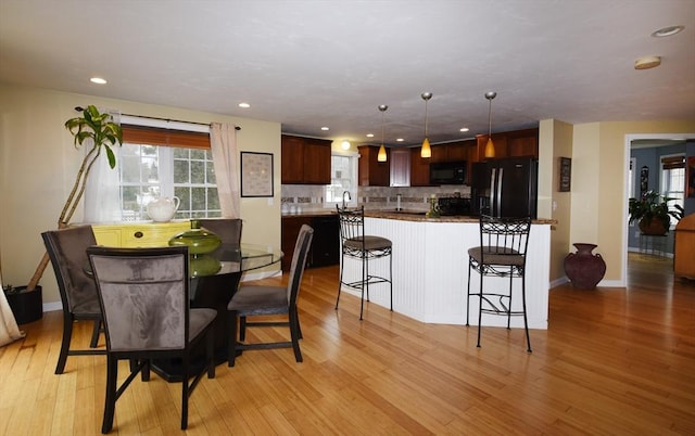 dining space featuring baseboards, light wood-style flooring, and recessed lighting