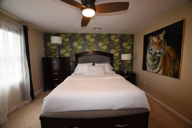 bedroom with light carpet, wallpapered walls, baseboards, visible vents, and ceiling fan