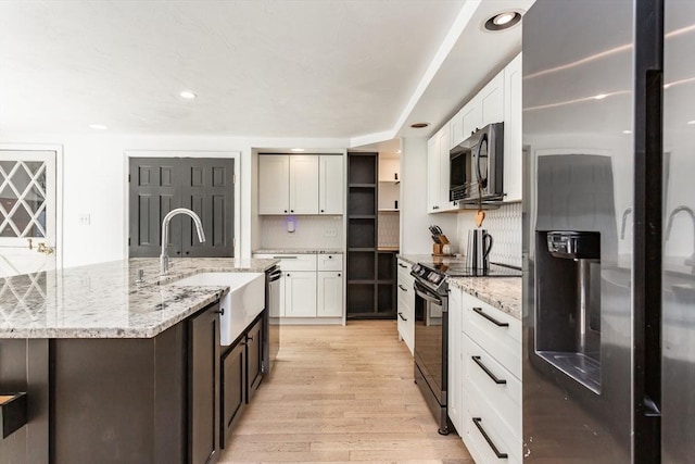 70 Oak St, Norton, MA 02766 - kitchen featuring stainless steel appliances, light wood-style floors, open shelves, decorative backsplash, and white cabinetry