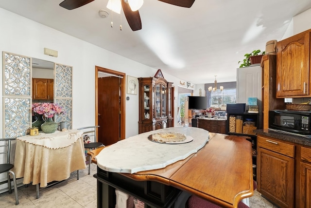 kitchen featuring ceiling fan with notable chandelier, light tile patterned floors, and hanging light fixtures