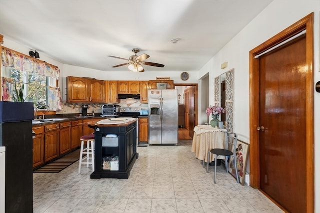 kitchen with ceiling fan, tasteful backsplash, a kitchen breakfast bar, a kitchen island, and appliances with stainless steel finishes