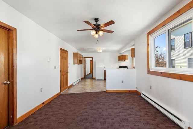 tiled spare room featuring ceiling fan and baseboard heating