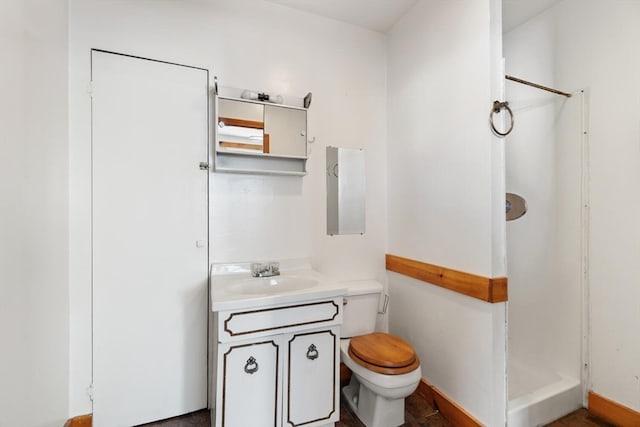 bathroom featuring toilet, vanity, and walk in shower