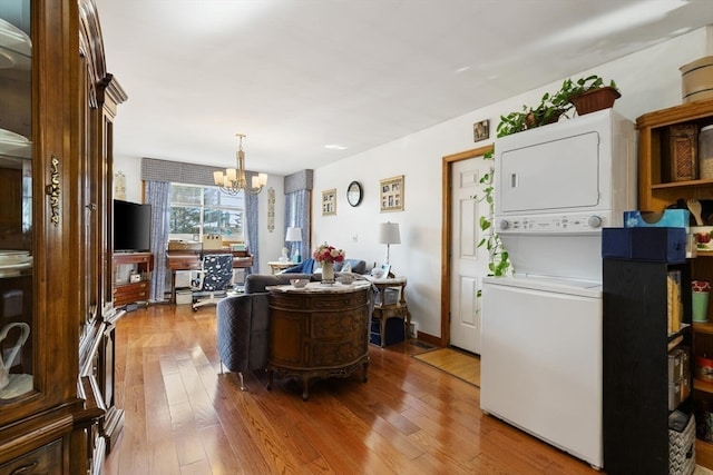 kitchen with a chandelier, stacked washer / dryer, hanging light fixtures, and light hardwood / wood-style flooring