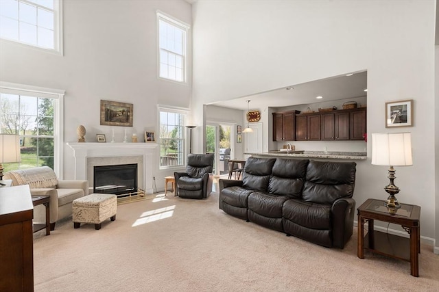 8 Heartwood Way Unit 8, Hopkinton, MA 01748 - living room featuring light carpet, a towering ceiling, healthy amount of natural light, a glass covered fireplace, and baseboards