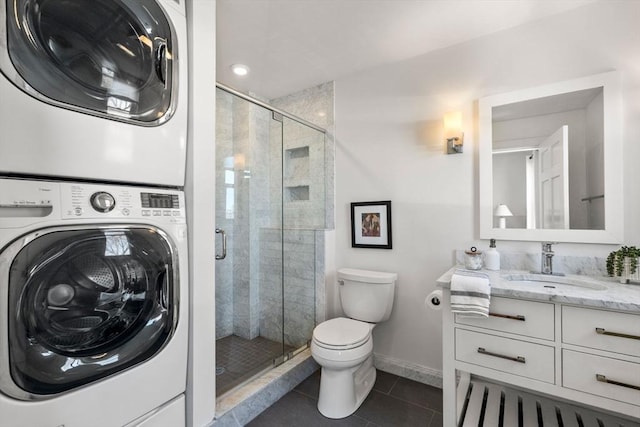 bathroom featuring an enclosed shower, vanity, stacked washing maching and dryer, and tile patterned flooring