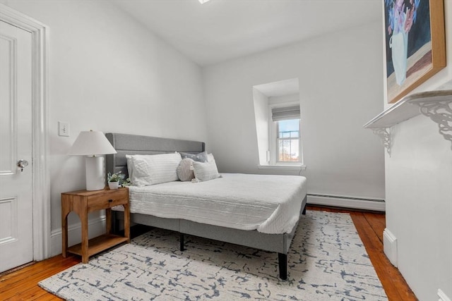 bedroom with hardwood / wood-style floors and a baseboard heating unit