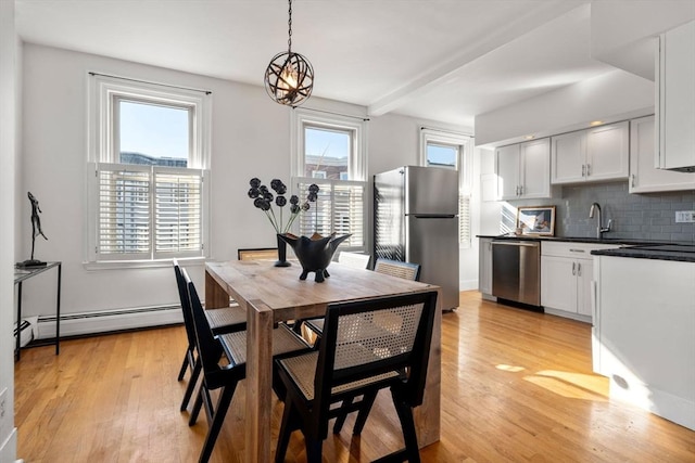 dining space with light hardwood / wood-style floors, baseboard heating, plenty of natural light, and an inviting chandelier