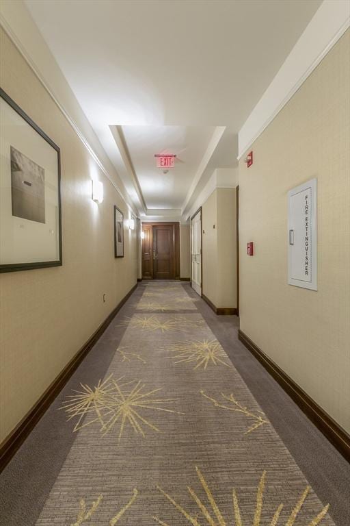 hallway with a raised ceiling and dark carpet