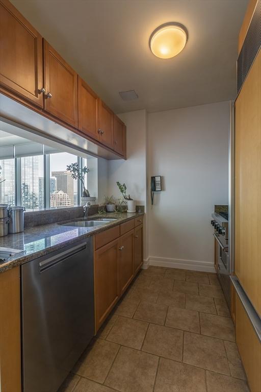 kitchen with light tile patterned flooring, stainless steel dishwasher, and sink