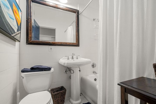 bathroom with tile walls, toilet, shower / bath combo, and a sink