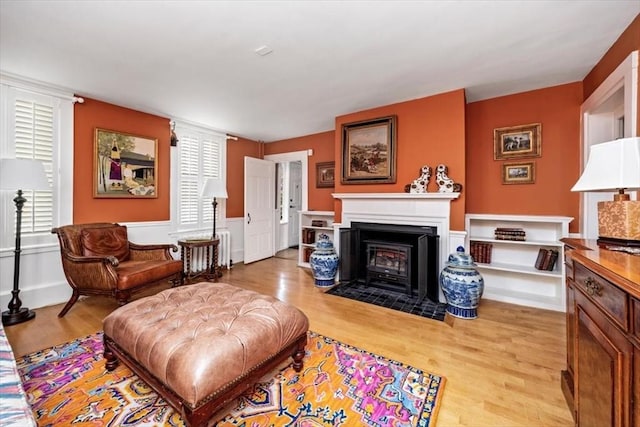 685 Highland St, Marshfield, MA 02050 - living room with light wood-type flooring, healthy amount of natural light, radiator, a fireplace with flush hearth, and a wainscoted wall