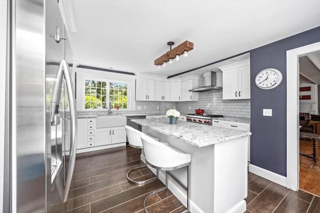 685 Highland St, Marshfield, MA 02050 - kitchen with stainless steel appliances, wall chimney exhaust hood, dark wood-style flooring, a kitchen island, and white cabinetry