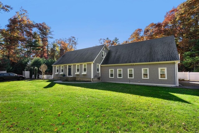 view of front of house with fence, a chimney, and a front lawn