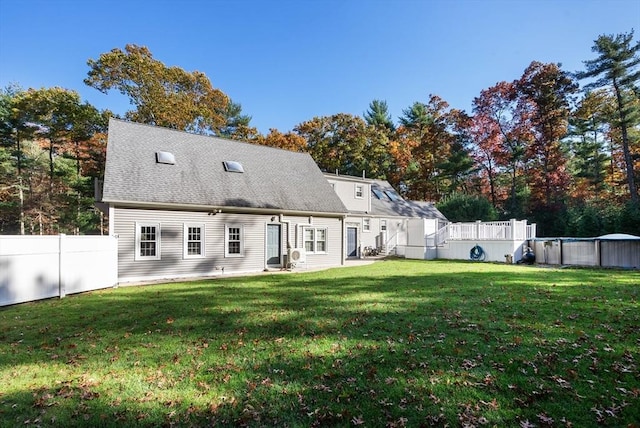 back of house featuring a shingled roof, a lawn, fence, and an outdoor pool