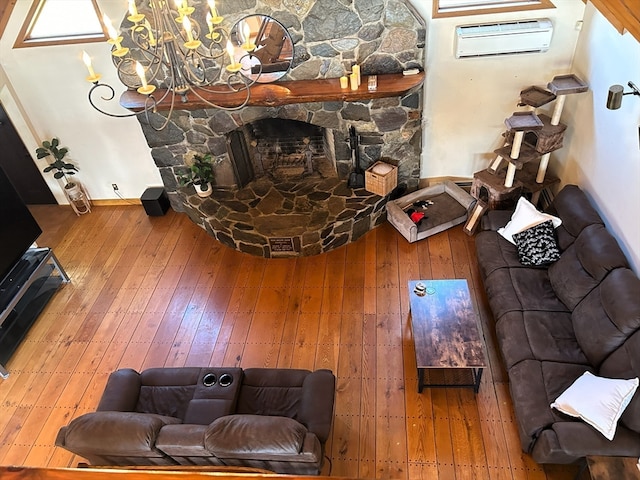 living room with an AC wall unit, wood-type flooring, a chandelier, and a fireplace