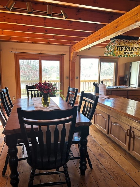 dining area with beamed ceiling, a wealth of natural light, and hardwood / wood-style flooring