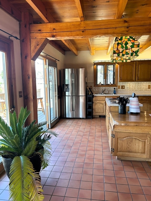 kitchen featuring backsplash, beam ceiling, light tile floors, and stainless steel refrigerator with ice dispenser