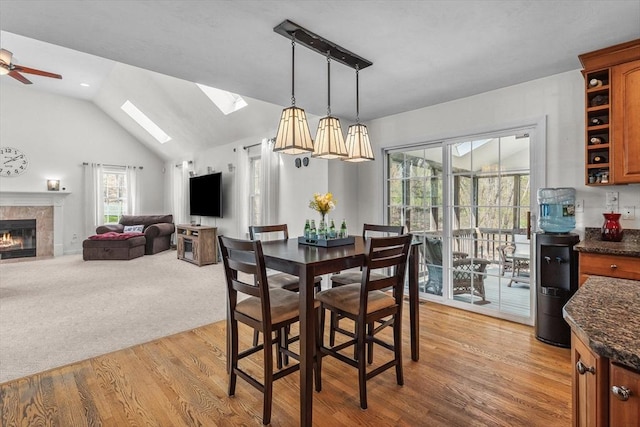 dining area with plenty of natural light, a ceiling fan, light wood-style flooring, and a fireplace