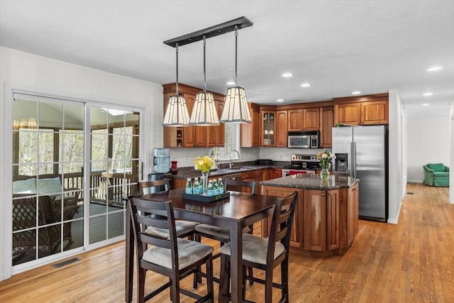 kitchen with visible vents, appliances with stainless steel finishes, brown cabinets, and a center island