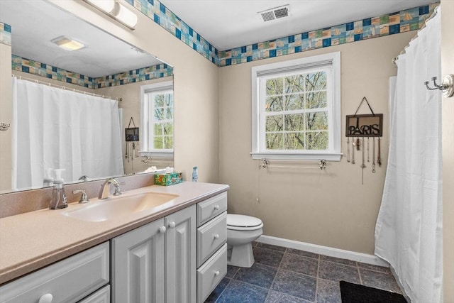 bathroom with baseboards, visible vents, toilet, and a wealth of natural light