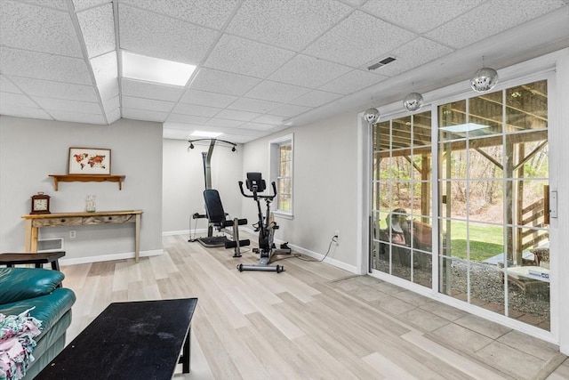exercise area with a paneled ceiling, baseboards, visible vents, and wood finished floors