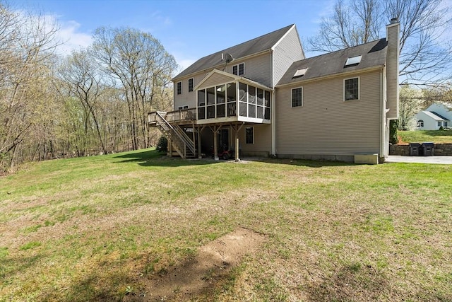 rear view of property with a chimney, a lawn, a deck, a sunroom, and stairs
