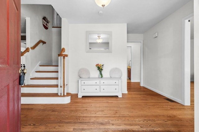 foyer with stairs, baseboards, visible vents, and wood finished floors