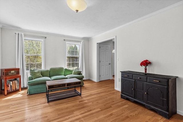 living area with crown molding, light wood-style floors, and baseboards