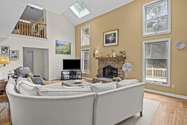 63 Forge Rd, Sharon, MA 02067 - living area with high vaulted ceiling, a skylight, hardwood / wood-style floors, a brick fireplace, and plenty of natural light