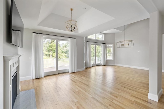 16 Pine Hill Rd Unit 16, Wenham, MA 01984 - unfurnished living room with a chandelier, light wood-style flooring, a tray ceiling, and a high end fireplace