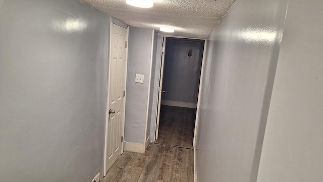 hallway with light wood-type flooring and a textured ceiling