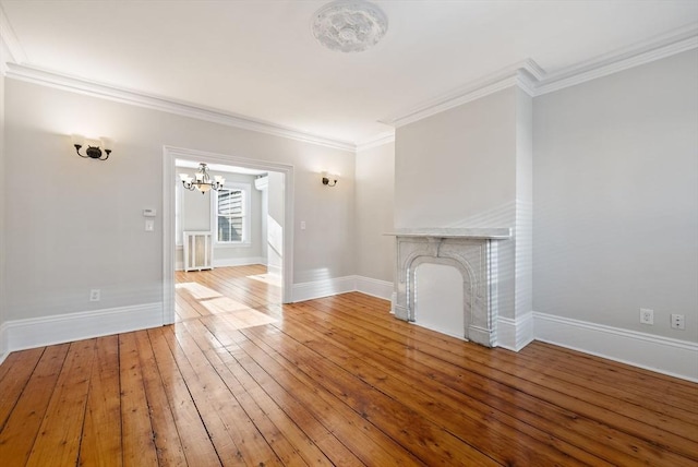 unfurnished living room featuring a fireplace, crown molding, baseboards, and wood-type flooring