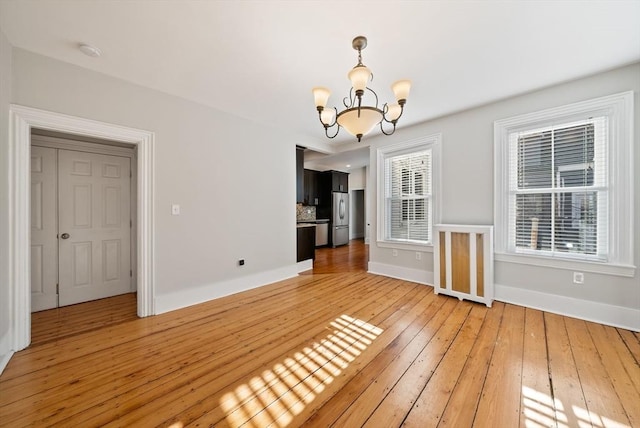 interior space with light wood-style flooring, baseboards, and an inviting chandelier